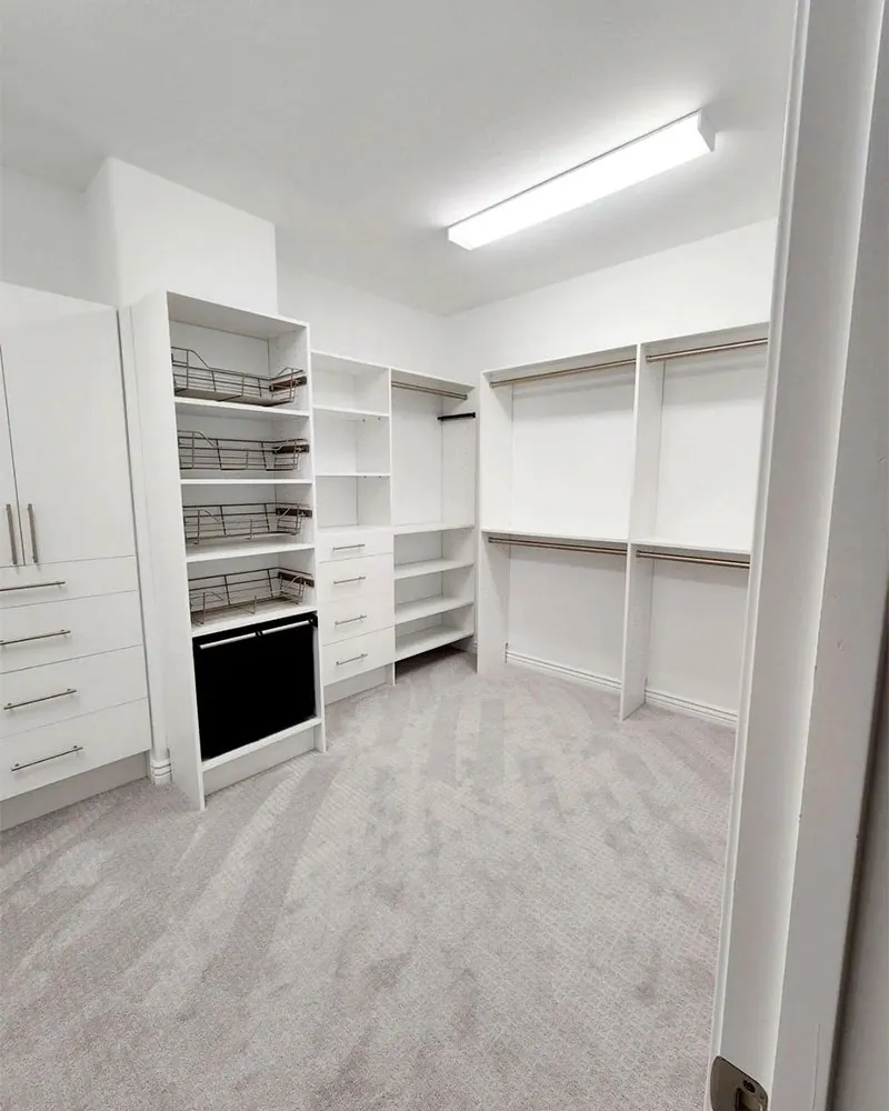 Bright custom walk-in closet with pull-out wire baskets, drawers, and a built-in compartment